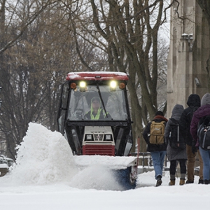 A snowplow shoveling snow on campus