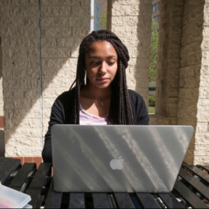 Female student working on a laptop outside