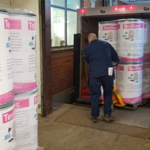 A Pitt Logistics and Printing Services employee loads the wrapped textiles bins into a truck for delivery. 