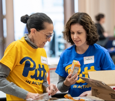Two people in Pitt shirts help pack boxes